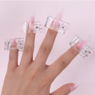 Mão com unhas postiças cor-de-rosa em clips transparentes