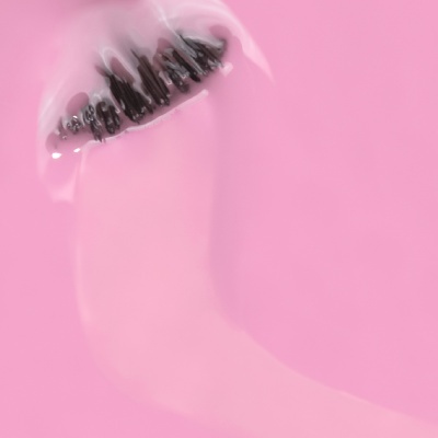 Lábio com gloss transparente brilhoso e unhas pretas sobre fundo cor-de-rosa