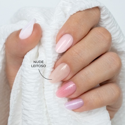 Mãos com unhas pintadas em tons suaves, segurando tecido branco.