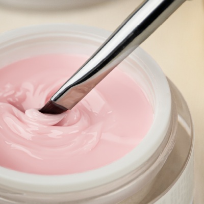 Creme rosa espesso em frasco aberto com pincel metálico inserido