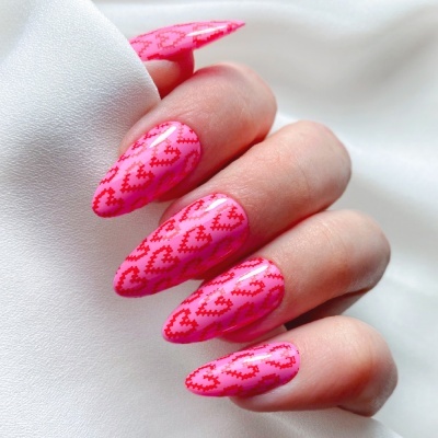 Unhas rosas com padrão de corações vermelhos