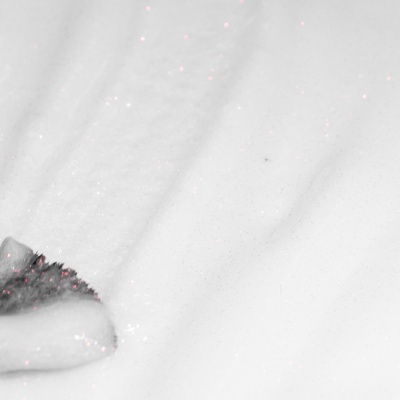 Gel branco com partículas rosadas e textura de bolhas numa superfície lisa