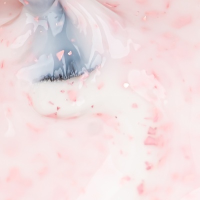 Pincel com cerdas pretas em substância cremosa branca com partículas cor-de-rosa.