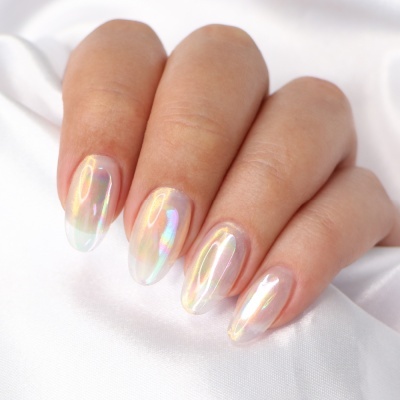 Unhas artificiais iridescentes em pele clara sobre tecido branco