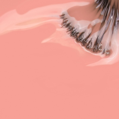 Pincel de maquilhagem com líquido cor-de-rosa fluido em fundo rosa