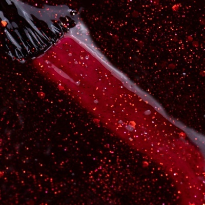 Pincel a aplicar verniz de unhas vermelho com glitter