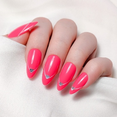Unhas artificiais em rosa fluorescente com corações prateados sobre fundo branco satin.