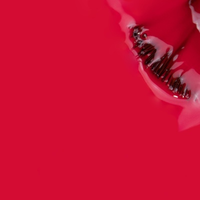 Pincel de maquilhagem com cerdas pretas num líquido vermelho