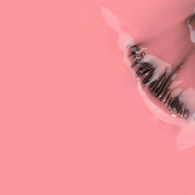Pincel de pestanas com creme cor de rosa num fundo rosa