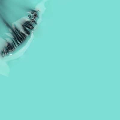Pincel de maquilhagem com cerdas pretas em líquido transparente sobre fundo azul celeste