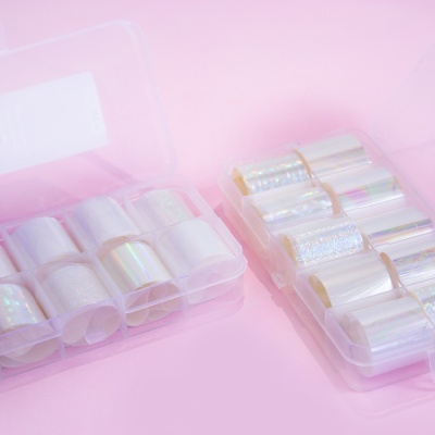 Caixas transparentes com rolos de película holográfica e brilhante sobre fundo rosa