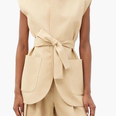 Conjunto bege com colete sem mangas e calças largas.