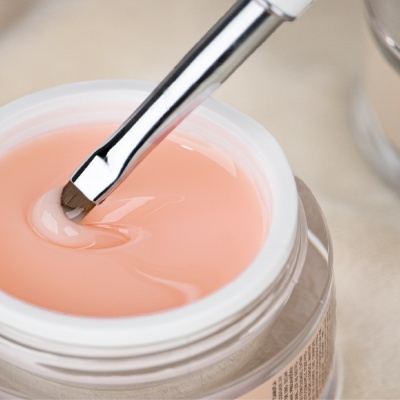 Frasco aberto de gel cor-de-rosa com pincel metálico