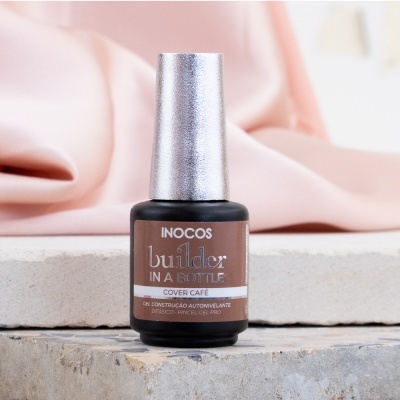 Frasco de verniz gel Inocos builder in a bottle Cover Café com tampa prateada sobre base de cimento