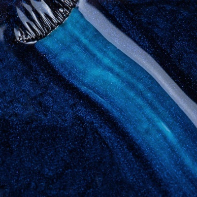 Pincel a aplicar tinta azul cintilante em fundo azul escuro brilhante