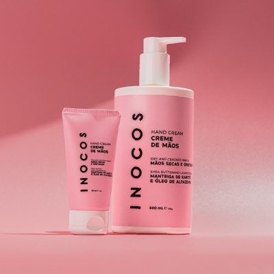 Dois frascos rosa de creme de mãos INOCOS com texto preto, em fundo rosa.