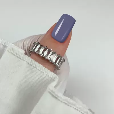 anel prateado com pedras retangulares em dedo com unha azul-púrpura
