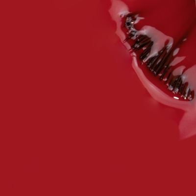Pente negro com creme branco sobre fundo vermelho.