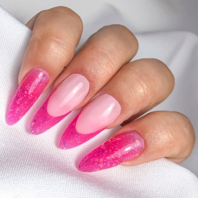 Unhas decoradas com gel rosa e glitter sobre fondo branco.