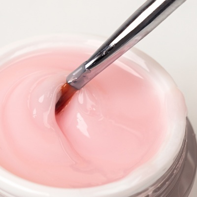 Pote aberto com gel rosa translúcido e pincel metálico