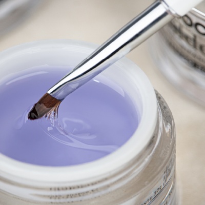 Frasco aberto de gel roxo com pincel molhado no gel