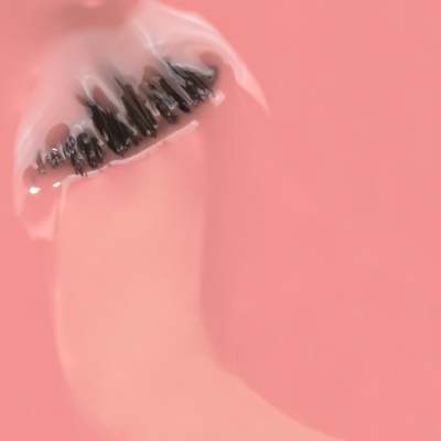 Dedo com unhas pintadas de preto cobertas por líquido transparente, fundo cor-de-rosa