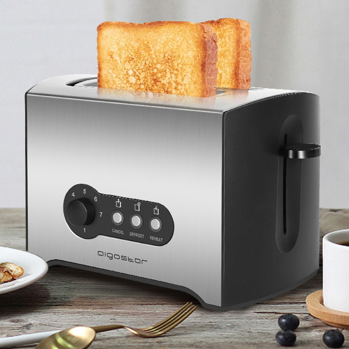 Torradeira metálica e preta com torradas, botões e seletor, numa mesa com frutos e café