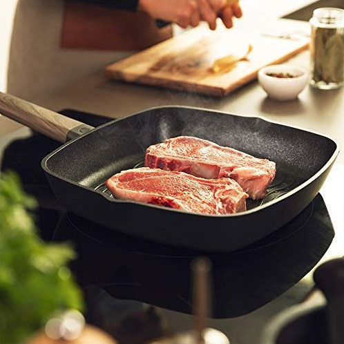 Frigideira quadrada preta com carne a cozinhar em fogão de indução