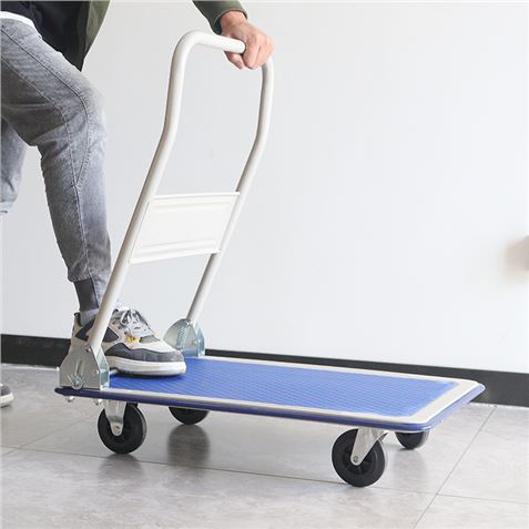 Carrinho de plataforma azul com estrutura metálica branca e rodas a ser empurrado por pessoa com calças cinzentas e ténis