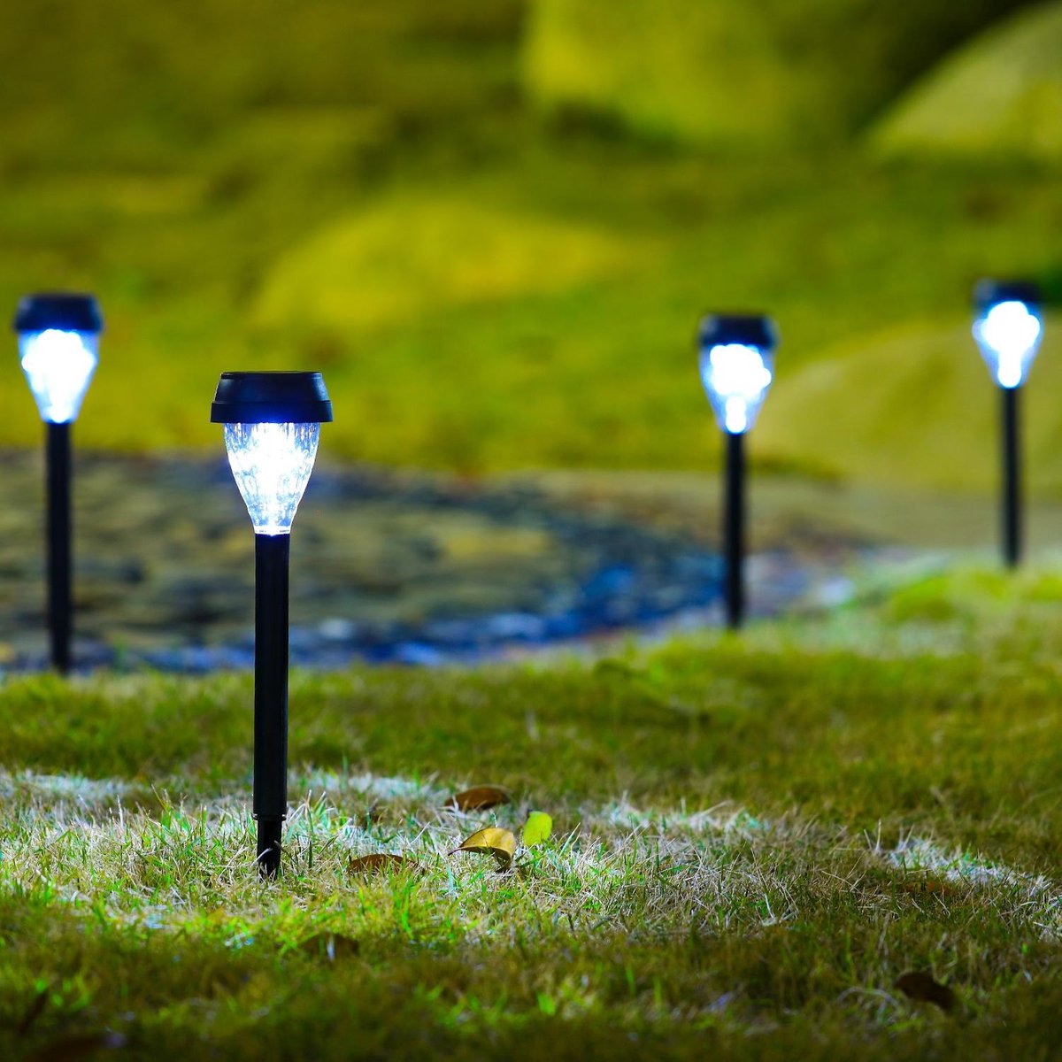 Luzes solares de jardim pretas acesas em relva verde durante a noite