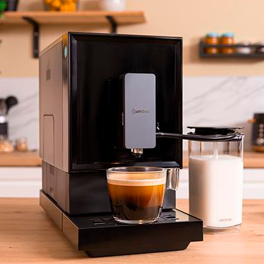 Máquina de café expresso preta com café e jarra de leite numa cozinha