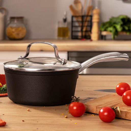 Panela preta antiaderente com tampa de vidro e pega metálica numa cozinha moderna