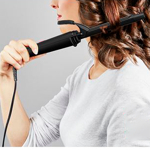 Pessoa a usar modelador de cabelo preto em cabelo castanho ondulado