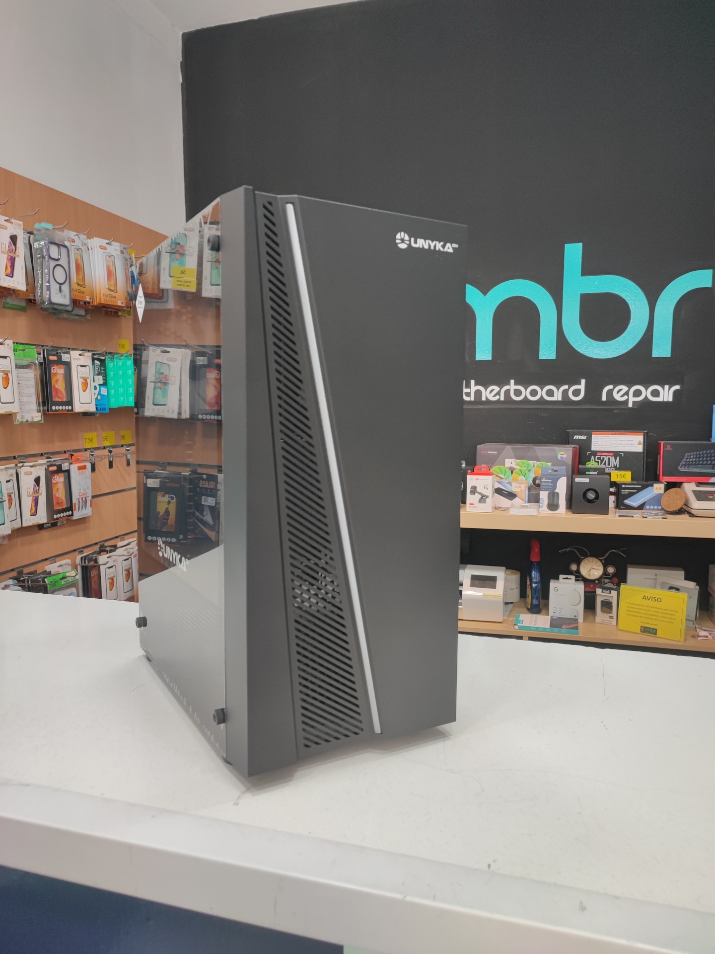 Computador de secretária preto com painel lateral em vidro sobre mesa branca numa loja