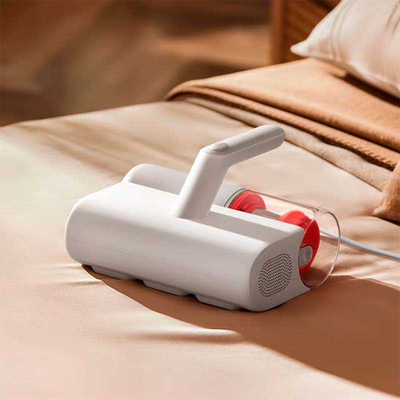 Aspirador portátil branco com detalhe vermelho sobre sofá ou cama bege
