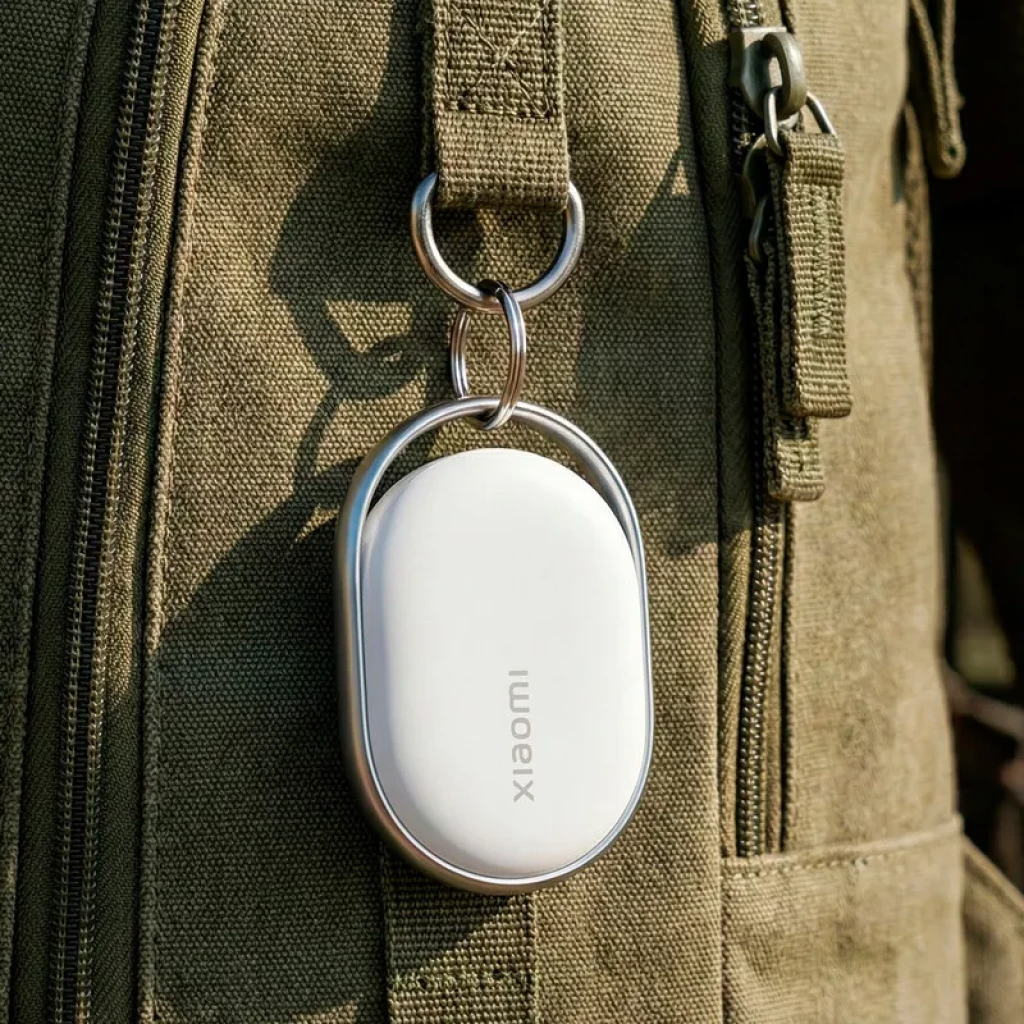 Dispositivo branco Xiaomi com estojo oval pendurado em mochila verde oliva.