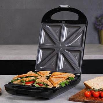 Grill elétrico aberto com sanduíches e tomates cherry ao lado