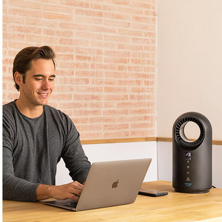 Homem a usar portátil Apple num ambiente com aparelho elétrico preto e parede de tijolos no fundo