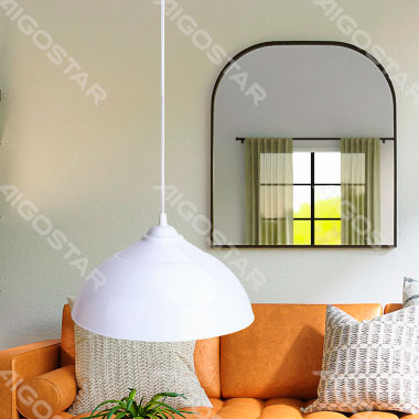 Candeeiro pendente branco sobre sofá laranja com almofadas e espelho na parede
