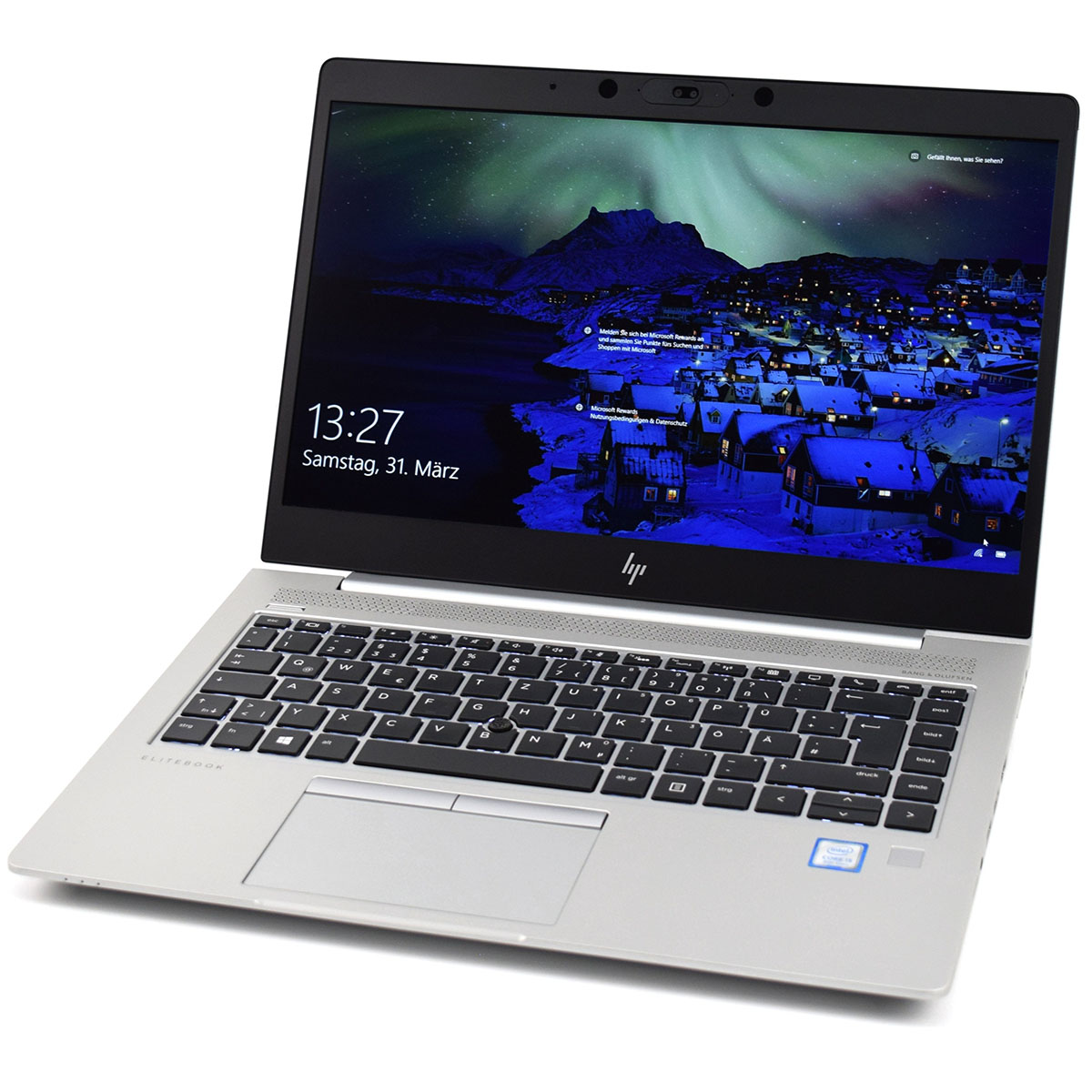 Portátil HP EliteBook prateado com teclado preto e ecrã a mostrar data, hora e imagem da noite