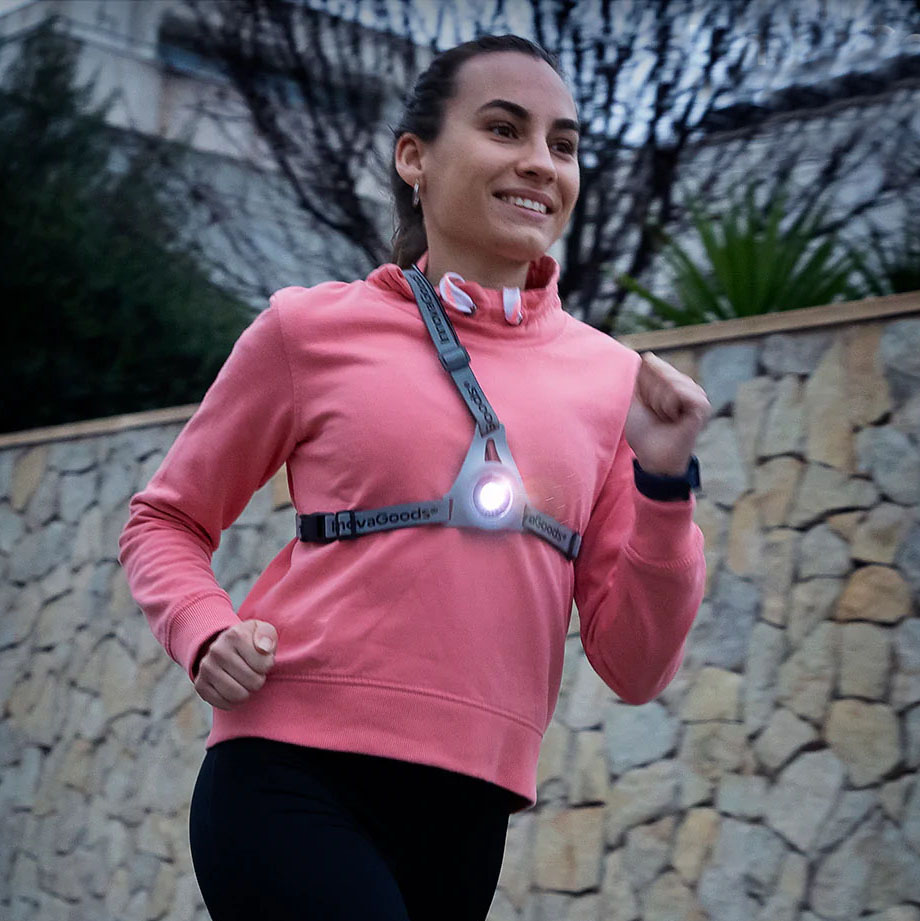 Mulher a correr com colete refletor cinzento com luz LED e sweatshirt rosa
