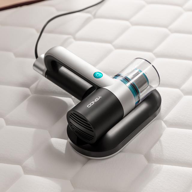 aspirador de pó portátil CONGA em preto e cinzento sobre colchão branco