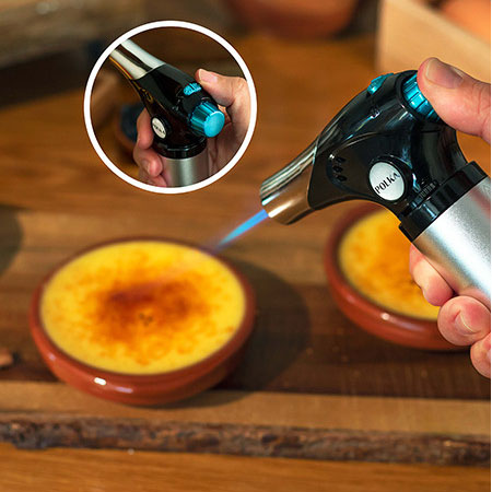 Maçarico de cozinha metálico e plástico queimando creme queimado em pratos de barro