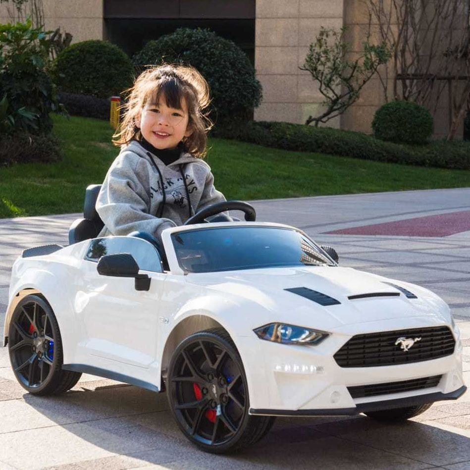 criança num carro elétrico infantil branco com volante e rodas negras