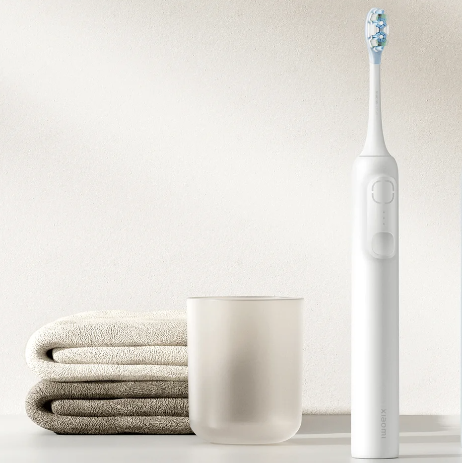 Escova de dentes elétrica branca com toalhas e copo translúcido