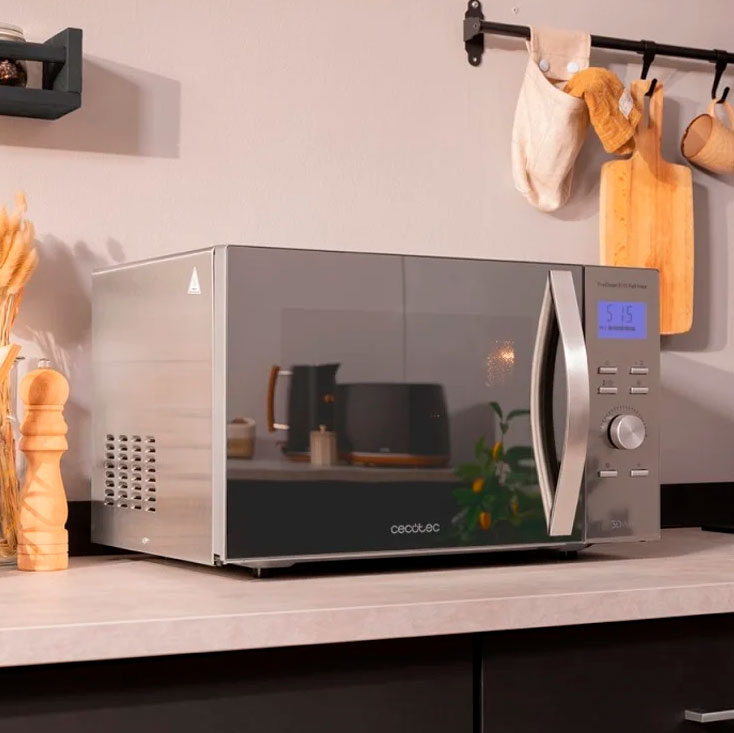 Micro-ondas prateado e preto Cecotec com visor digital azul na bancada da cozinha
