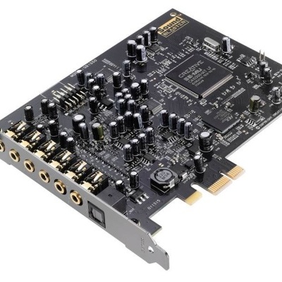 Placa de som preta com múltiplos componentes eletrónicos, conexões áudio douradas e texto Creative Sound Blaster