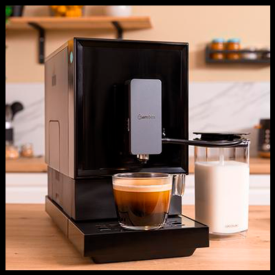 Máquina de café expresso preta com café e jarra de leite numa cozinha