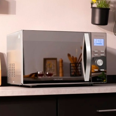 Micro-ondas cinza e preto Cecotec com visor digital e botões numa bancada de cozinha clara