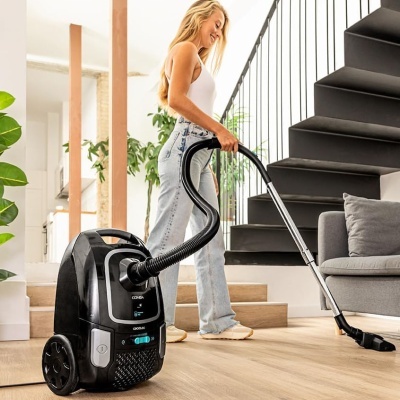 aspirador de pó preto com mulher a aspirar numa sala moderna